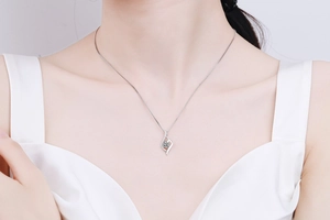 Detail shot of a s925 sterling silver heart necklace with moissanite on a model neck