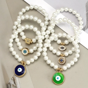 Detailaufnahme von weißen Perlenarmbändern mit bunten Evil-Eye-Anhängern aus Emaille