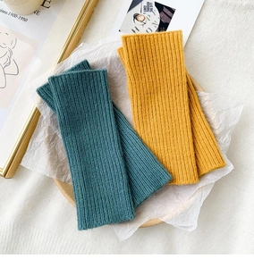 Macro view of blue and yellow ribbed knit arm warmers in a rustic wooden tray