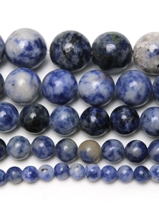 Macro shot of natural blue sodalite round beads with white quartz veins on fabric