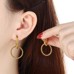 Detail of a model wearing a gold U-shaped earring with a twisted rope circle pendant