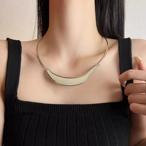Detailed view of a crescent moon pendant on a polished silver tube choker necklace