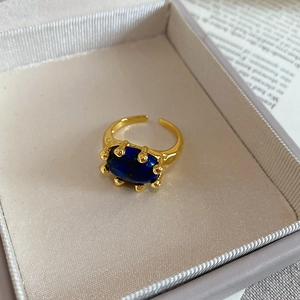 Detailed macro view of an oval lapis lazuli ring set in a gold plated adjustable band