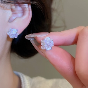 Close-up of light purple floral earrings with sparkling glitter and petal layers