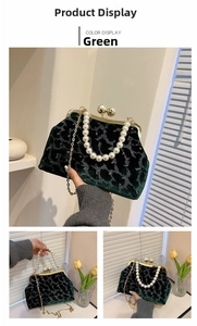 Detail of dark green velvet shell bag featuring pearl handle and gold chain strap