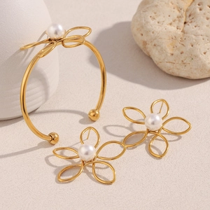 Détail du parure de bijoux fleur plaqué or 18 carats avec perles blanches sur fond beige