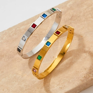 Western style gold and silver bangles with colorful square zircons on stone background