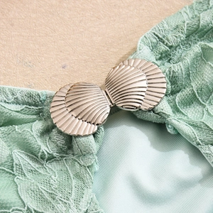 Close-up of shell-shaped metal buckle and mint green lace detail on backless dress