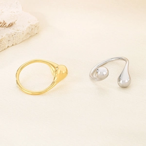 Detail of gold and silver teardrop open rings with spherical ends on stone