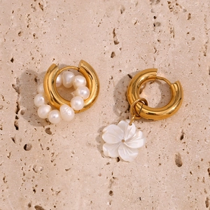 Close-up of asymmetric 18K gold earrings with white pearls and a delicate flower pendant