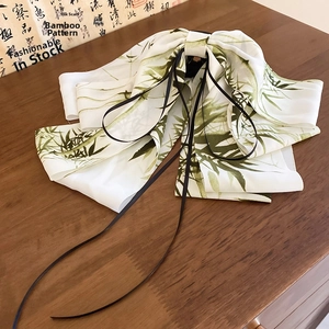 Detail of satin bow hair clip with bamboo leaf print and black ribbons on wood surface