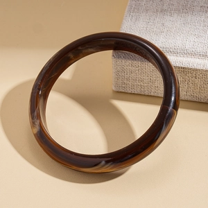 Detailed view of the dark tortoiseshell acrylic bangle with natural amber textures