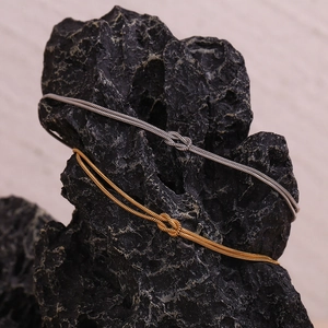 Detail of gold and silver knot snake chains draped on a textured black rock surface