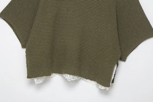 Close-up of army green knit top hem featuring white double-layer lace and side split detail
