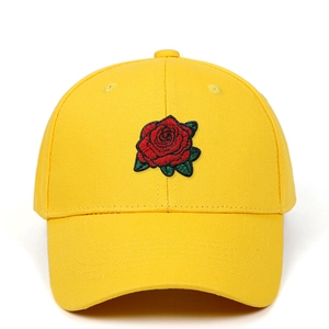 Détail de la broderie rose rouge sur le devant d'une casquette en coton jaune