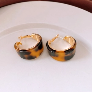 Detailed view of tortoiseshell resin C-shaped hoop earrings with 18K gold plated trim