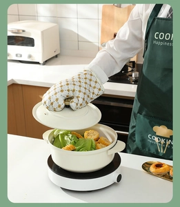 Heat resistant kitchen mitt with yellow geometric patterns lifting a cooking pot lid