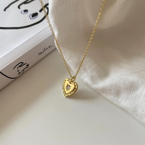 Detail of gold heart pendant necklace with starburst zircon on a minimalist background
