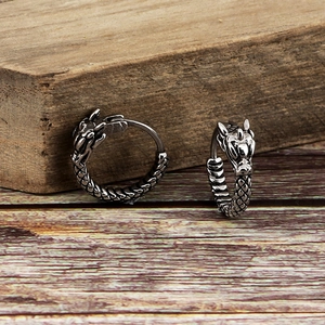Vintage silver dragon earrings with detailed scales and head design on wood background