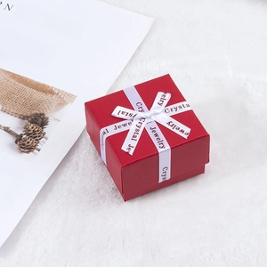 Détail de boîte à bijoux rouge carrée avec ruban blanc et texture grainée fine