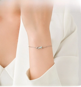 Detail view of a dainty silver bow bracelet with light blue ribbon and sparkling stones