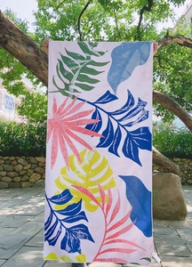 Detail of a large rectangular quick-dry beach towel with colorful tropical leaf prints