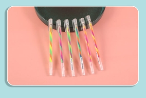 Detailed view of six colorful striped rainbow gel pens arranged on a pink surface