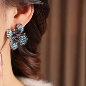 Vintage butterfly earrings with blue and purple stones worn by a model in soft lighting