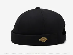 Vue latérale du bonnet Docker noir en coton avec badge en métal bronze et sangle réglable
