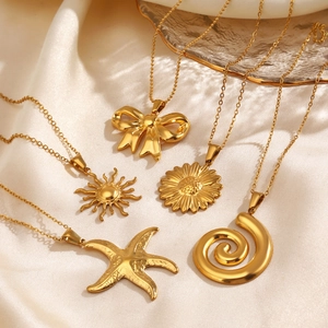 Golden necklace set with starfish, sun, and bow pendants on soft silk and glass backdrop