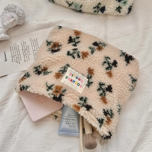 Detail of plush lamb wool floral cosmetic bag with embroidery and zipper storage