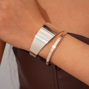Polished silver metal cuff bracelet set with wide and thin irregular open rings on wrist