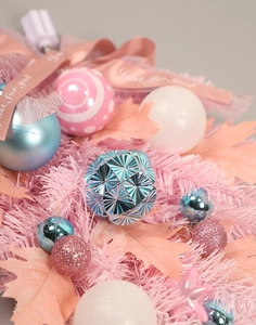 Dettaglio di decorazione natalizia rosa con palline blu e nastro 'Just for you'
