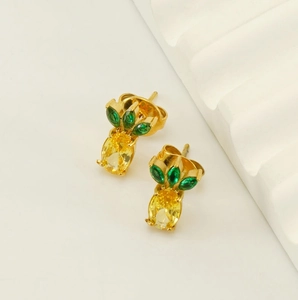 Macro view of 18k gold plated pineapple stud earrings with green and yellow zircons