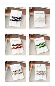 Detailed display of wavy acetate hair clips in six colors on white cards in a wooden tray