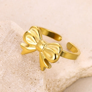 Detailed view of an adjustable golden bow ring placed on a natural stone surface