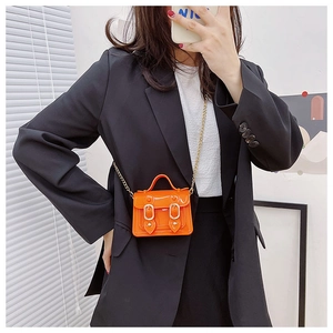 Mirror selfie showing a bright orange patent leather mini bag with gold chain strap