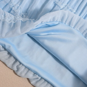 Detail of light blue backless dress showing lace trim and pleated fabric texture