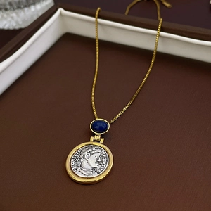 Detail of vintage gold chain with silver coin pendant and blue gemstone in a jewelry box