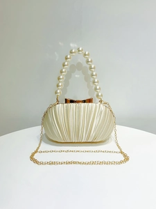 Detail der eleganten beigen Abendtasche mit Perlenkapitel und goldener Metallkette