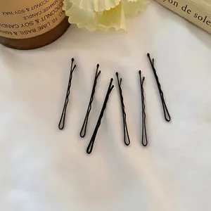 Lot de barrettes noires ondulées minimalistes présentées dans un décor élégant