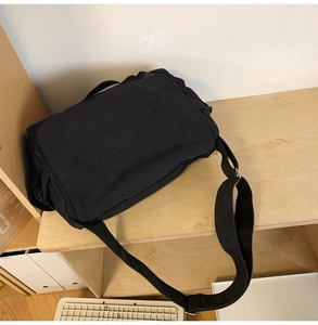 Macro detail of the durable black canvas crossbody bag with wide adjustable shoulder strap
