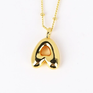 Close-up of golden puffy 3D letter A pendant on a delicate ball chain necklace