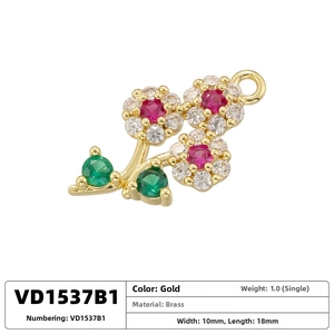 Macro detail of gold plated brass floral pendant with red stones and green leaves