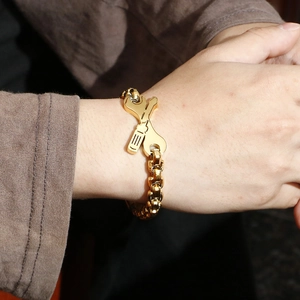 Detail of creative wrench and screwdriver cross pendant on gold chain for men