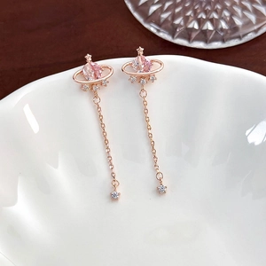 Detail of rose gold Saturn planet earrings with pink heart zircon and star tassels