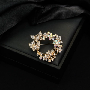 Elegant gold flower wreath brooch with sparkling crystals on black silk background