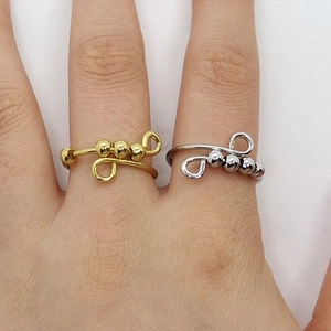 Close-up of gold and silver spinning bead rings worn on fingers for anxiety relief