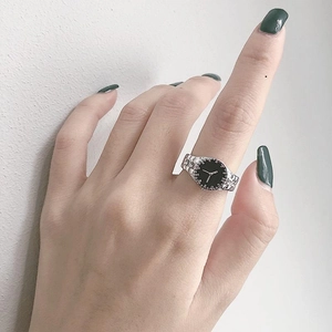 Creative watch-style ring featuring a black dial and silver band on a finger