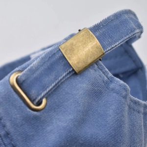 Close-up of blue washed denim baseball cap with adjustable brass metal buckle and strap